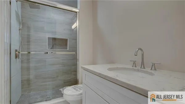 a view of a hallway with wooden floor and a bathroom