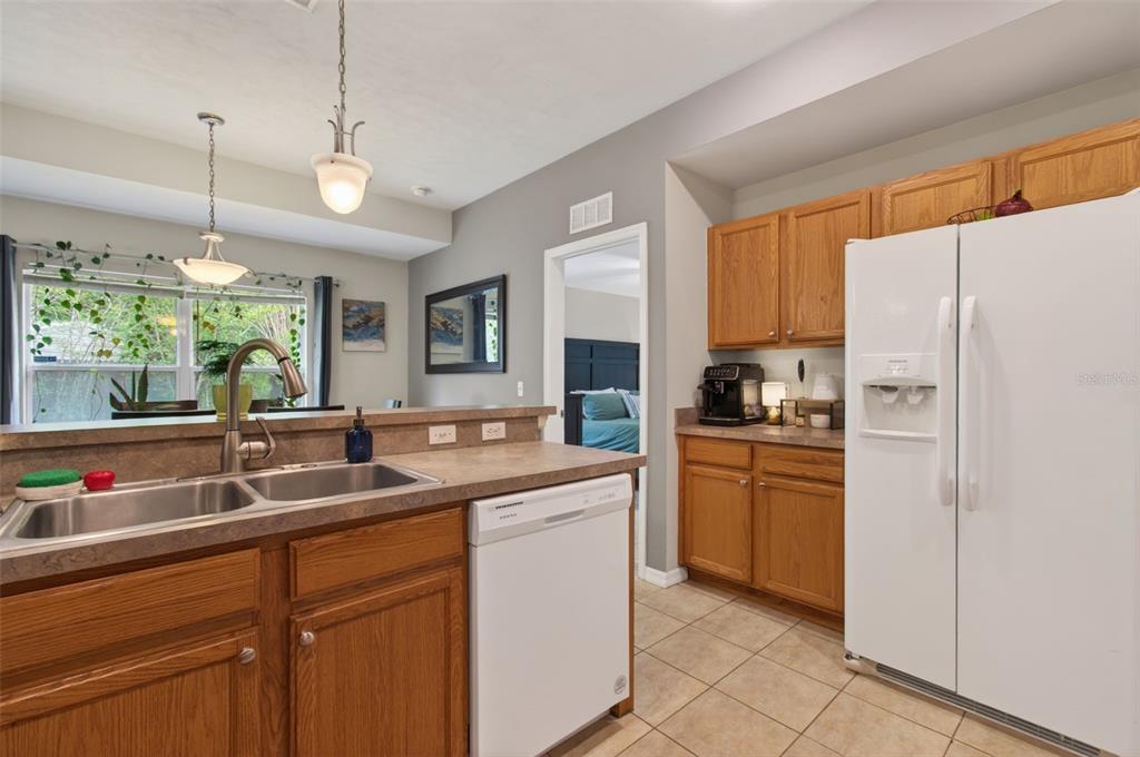 4729 Northeast 16th Terrace Gainesville, FL 32609 - Photo 7 of 41 a kitchen with stainless steel appliances granite countertop a sink a refrigerator a stove a dining table and chairs with wooden floor