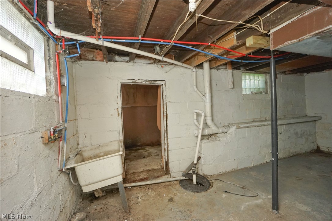 3443 Sheridan Road Youngstown, OH 44502 - Photo 16 of 24 Lower level utility space featuring exposed wood joists, concrete block walls, a utility sink, and visible plumbing and electrical infrastructure