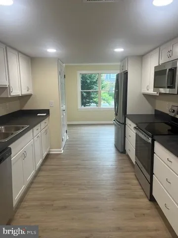 a kitchen with granite countertop wooden floors appliances and cabinets