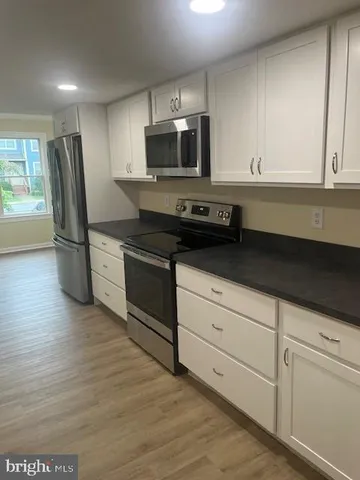 a kitchen with granite countertop white cabinets and stainless steel appliances