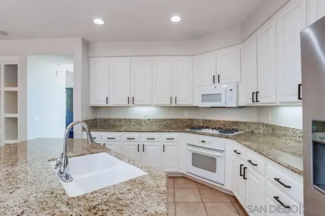 a kitchen with granite countertop white cabinets and white appliances
