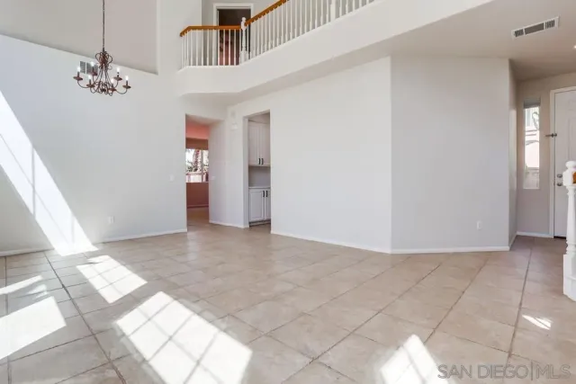 a view of an empty room with window and chandelier