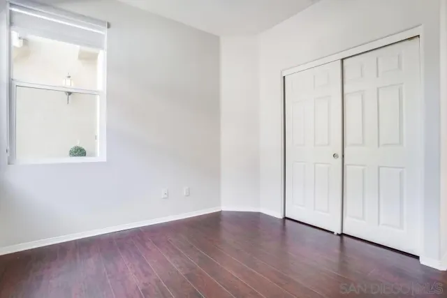 an empty room with wooden floor and closet area