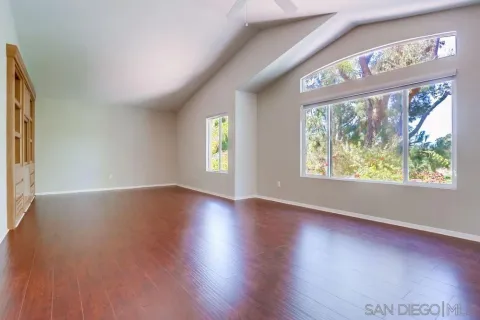 a view of an empty room with wooden floor and entryway