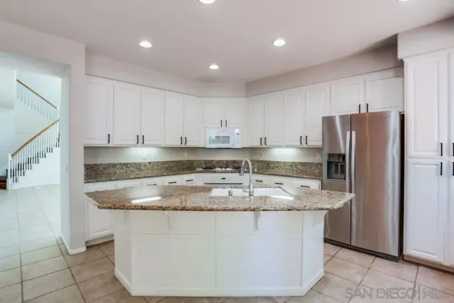 a kitchen with stainless steel appliances granite countertop a sink a refrigerator and a stove