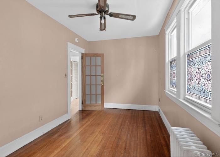 64 Watchogue Road Staten Island, NY 10314 - Photo 8 of 23 an empty room with wooden floor chandelier fan and windows