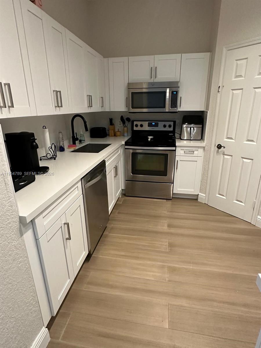 1948 Southeast 24th Avenue Homestead, FL 33035 - Photo 4 of 6 a kitchen with white cabinets and white appliances