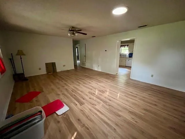 a kitchen with granite countertop a refrigerator oven a sink dishwasher and white cabinets with wooden floor