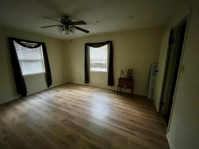 a view of an empty room with a window and wooden floor
