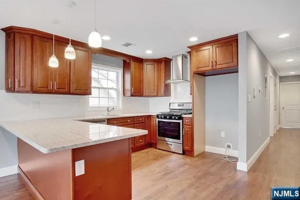 a kitchen with stainless steel appliances granite countertop a refrigerator a sink dishwasher and wooden cabinets with wooden floor