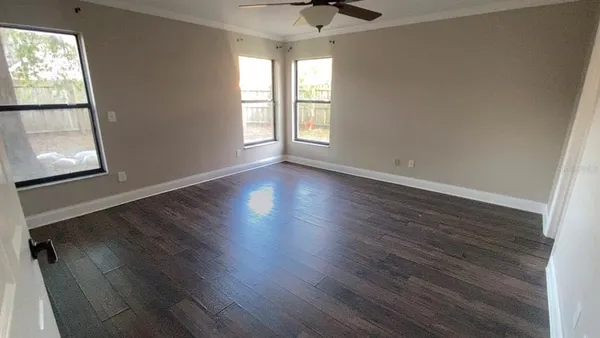 an empty room with wooden floor and windows