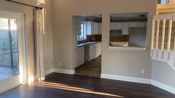 a kitchen with white cabinets and wooden floor