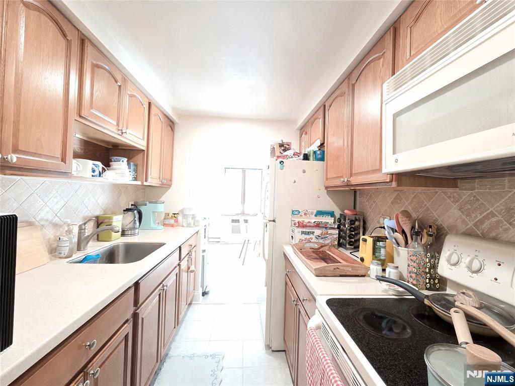 150 County Road, Unit 18 Tenafly, NJ 07670 - Photo 10 of 15 a kitchen filled a sink a stove and cabinets