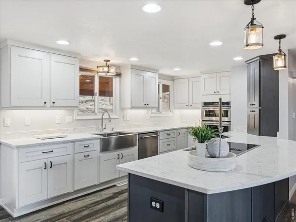 a kitchen with stainless steel appliances granite countertop a sink dishwasher and white cabinets with wooden floor