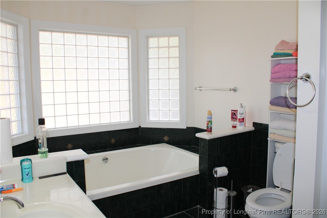 573 Porter Road Hope Mills, NC 28348 - Photo 16 of 29 a bathroom with a granite countertop sink a toilet a large mirror and a bathtub