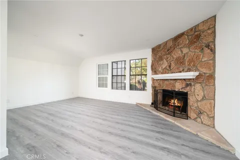 a view of an empty room with wooden floor fireplace and a window
