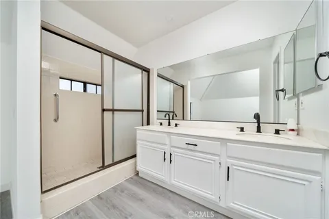 a spacious bathroom with a double vanity sink a mirror and a shower