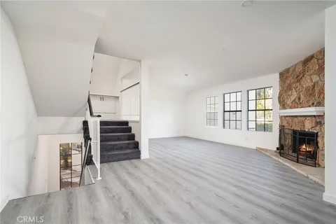 an empty room with wooden floor fireplace and windows