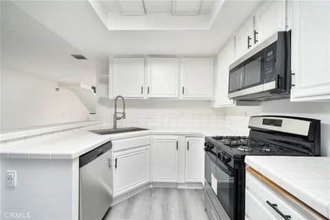 a kitchen with cabinets stainless steel appliances a sink and wooden floor