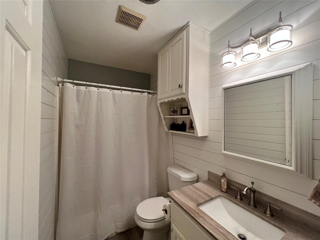 1337 South 11th Street Waco, TX 76706 - Photo 12 of 12 a bathroom with a sink a toilet a mirror and shower curtain