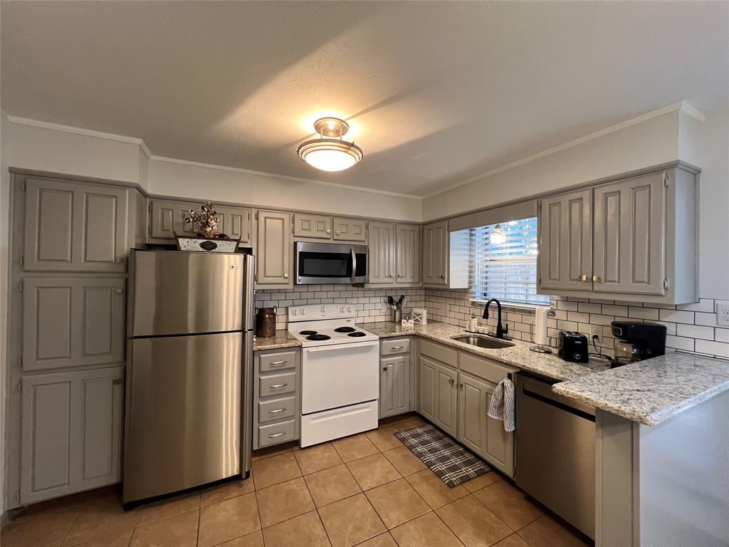 1337 South 11th Street Waco, TX 76706 - Photo 3 of 12 a kitchen with a sink a refrigerator a microwave a stove and cabinets