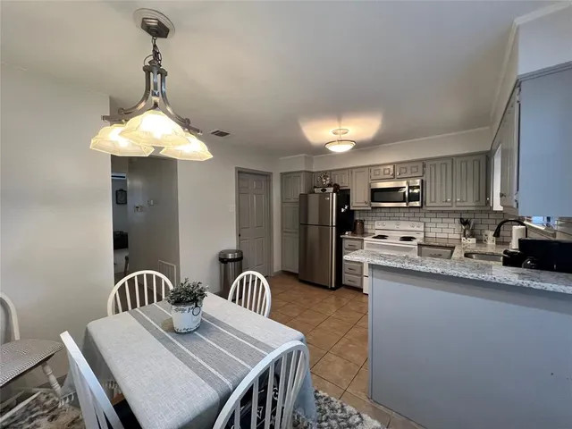 a kitchen with stainless steel appliances granite countertop a sink dishwasher a stove a refrigerator with a dining table and chairs