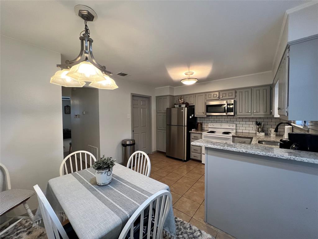 1337 South 11th Street Waco, TX 76706 - Photo 6 of 12 a kitchen with stainless steel appliances granite countertop a sink dishwasher a stove a refrigerator with a dining table and chairs