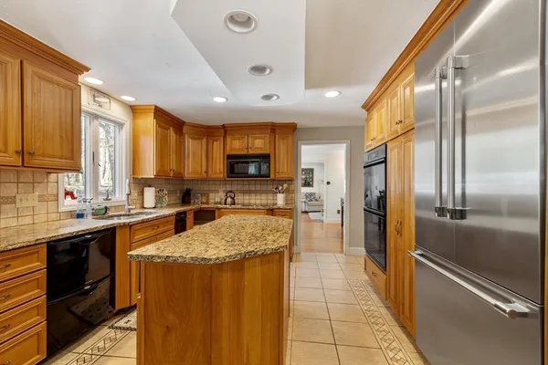 a kitchen with stainless steel appliances granite countertop refrigerator a sink a stove top oven and a dishwasher next to a window