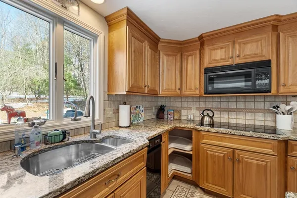 a kitchen with granite countertop a sink a counter space cabinets and stainless steel appliances