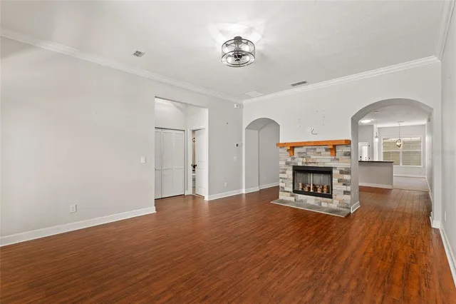 an empty room with wooden floor fire place and windows