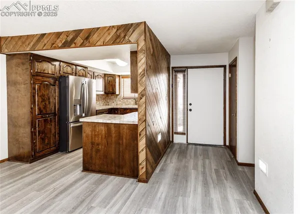 a kitchen with a refrigerator and wooden floor