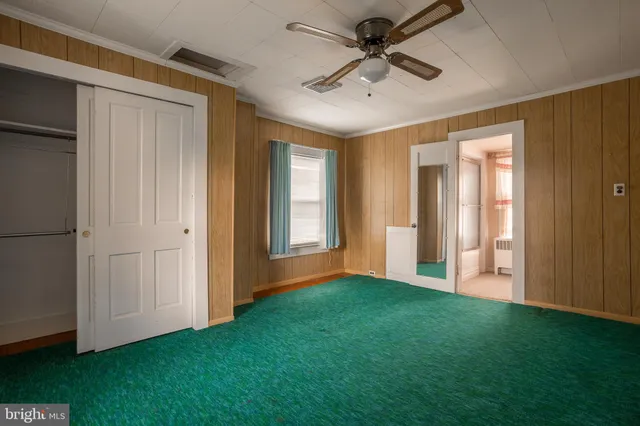 a view of a livingroom with a chandelier fan and windows