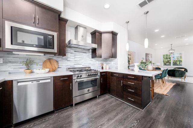 a kitchen with stainless steel appliances granite countertop a stove a sink dishwasher and a microwave oven with wooden cabinets