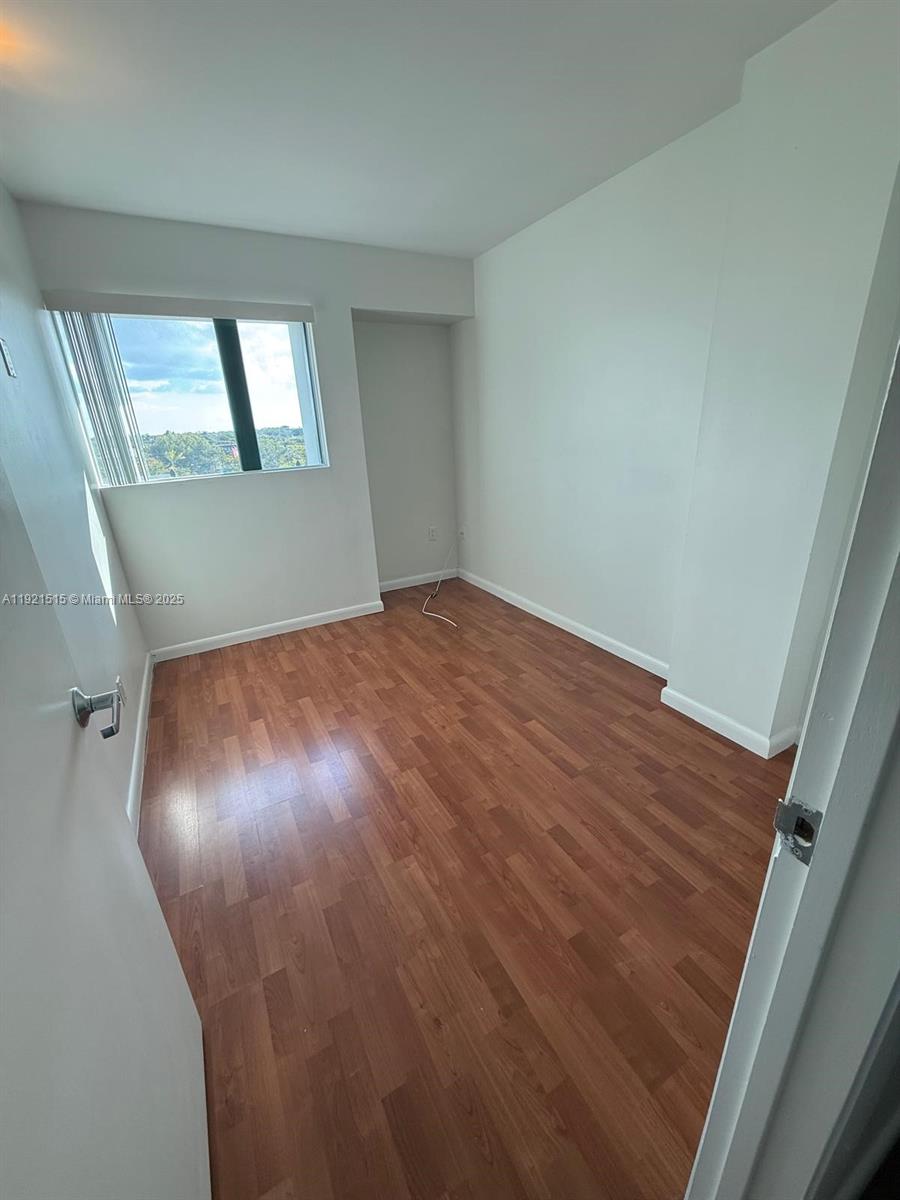 5783 Southwest 72nd Street, Unit 5783 South Miami, FL 33143 - Photo 2 of 4 an empty room with wooden floor and windows