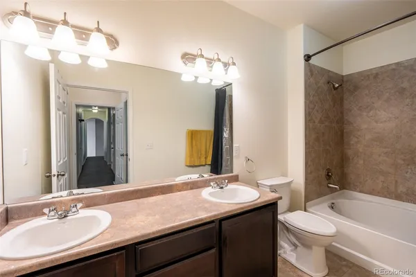 a bathroom with a granite countertop sink a toilet a mirror a vanity and shower