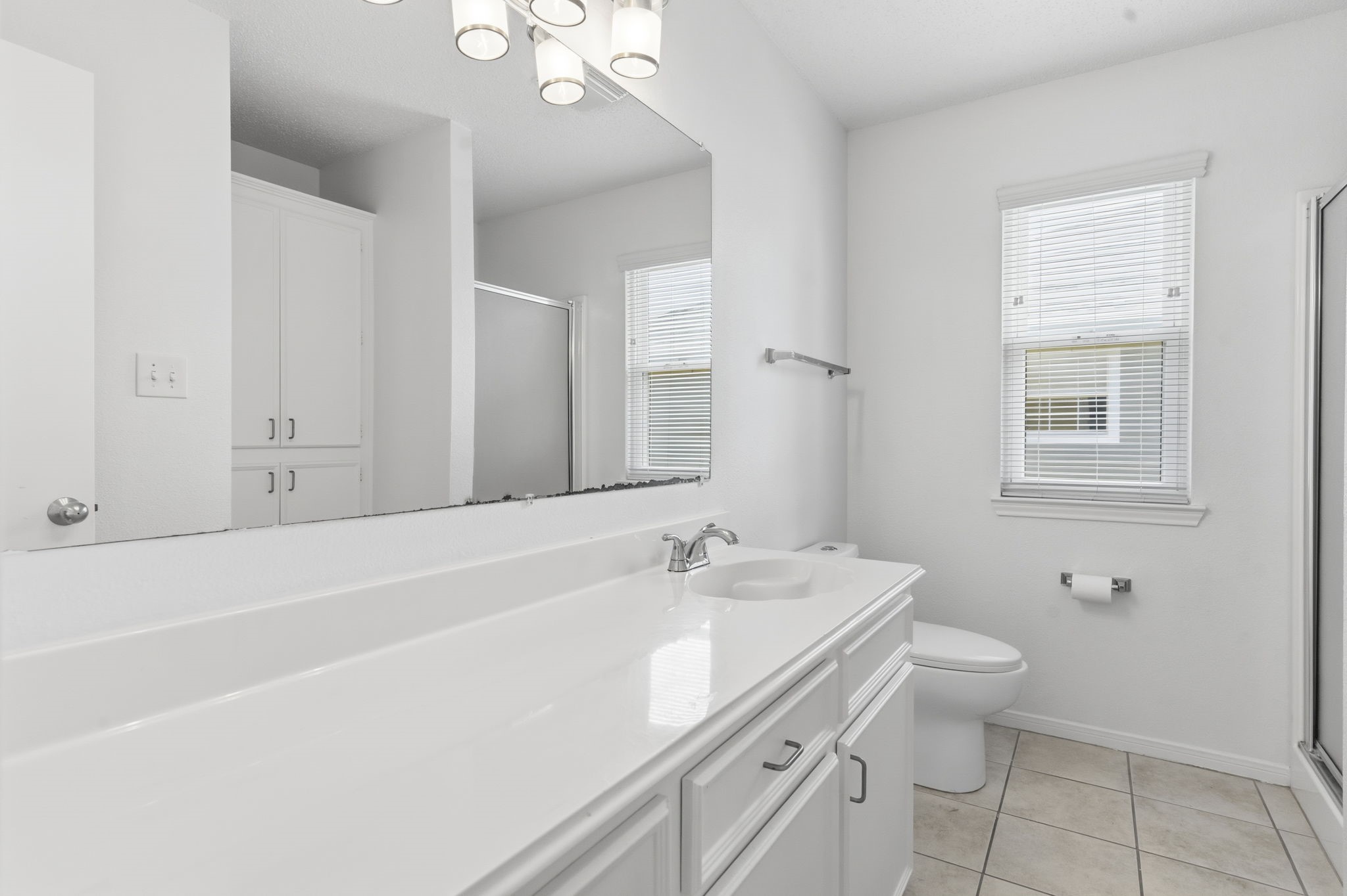 119 Sand Shoals Road Freeport, TX 77541 - Photo 22 of 34 Full bath — long single-sink vanity with extended counter and built-in linen storage, vanity bar lighting, walk-in glass shower, and tile flooring.