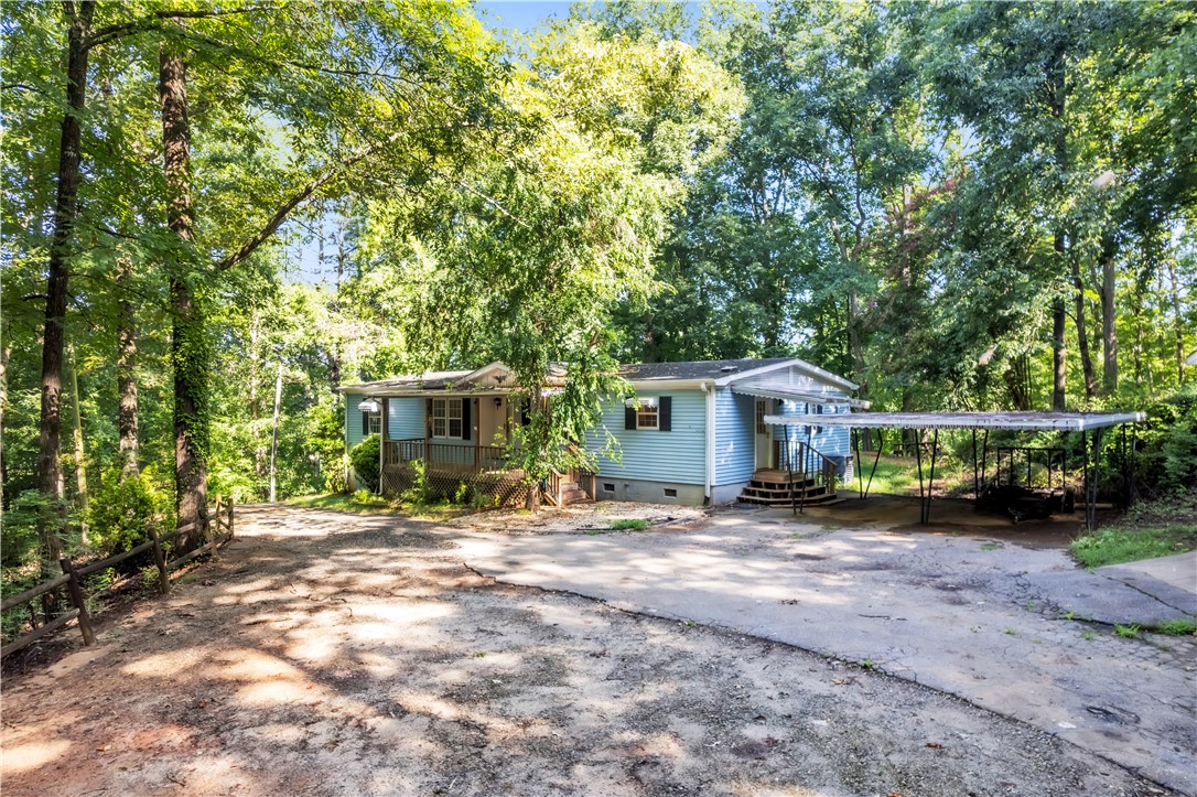 178 Childress Road Pickens, SC 29671 - Photo 24 of 32 A welcoming front porch and carport enhance this cozy home nestled among abundant greenery.