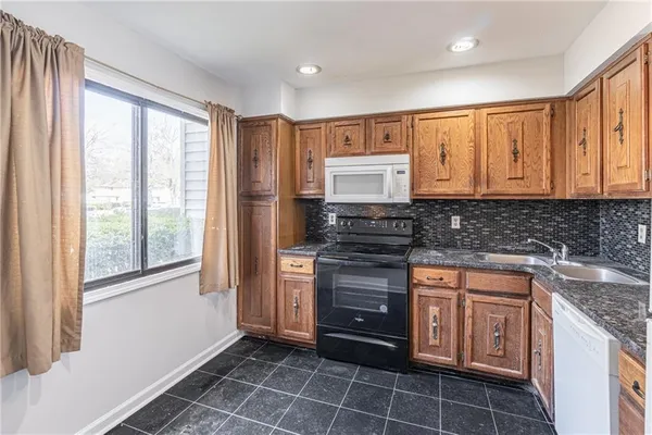 a kitchen with granite countertop a sink stove and cabinets