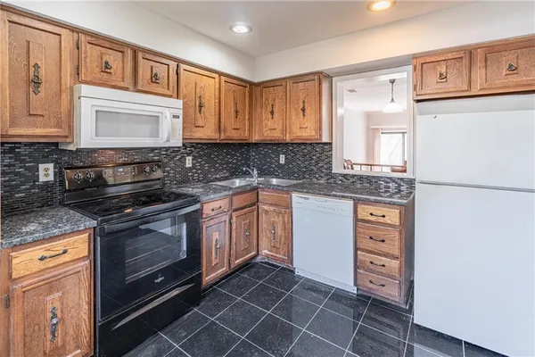 a kitchen with granite countertop a sink stove and cabinets