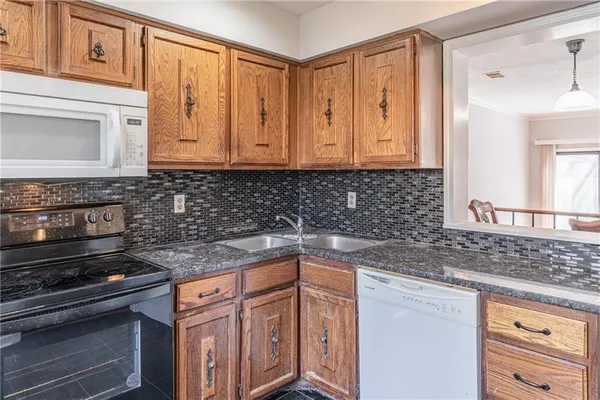 a kitchen with granite countertop a refrigerator a sink and white cabinets