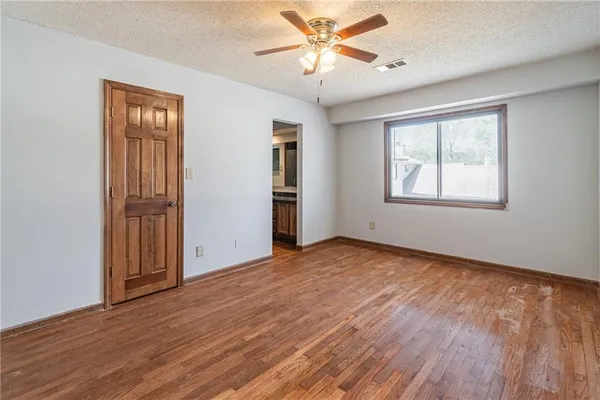 an empty room with wooden floor and a ceiling fan