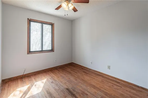 an empty room with wooden floor closet and windows