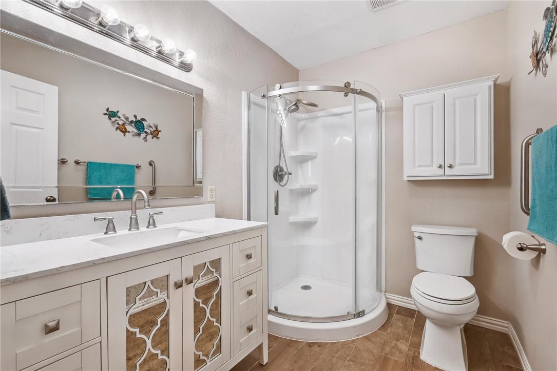 4957 Shadowbend Drive Corpus Christi, TX 78413 - Photo 6 of 35 a bathroom with a granite countertop sink a toilet a mirror a vanity and shower