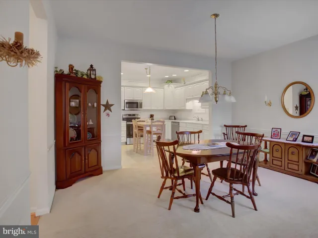 a view of a dining room and livingroom with furniture wooden floor a rug a painting and a chandelier