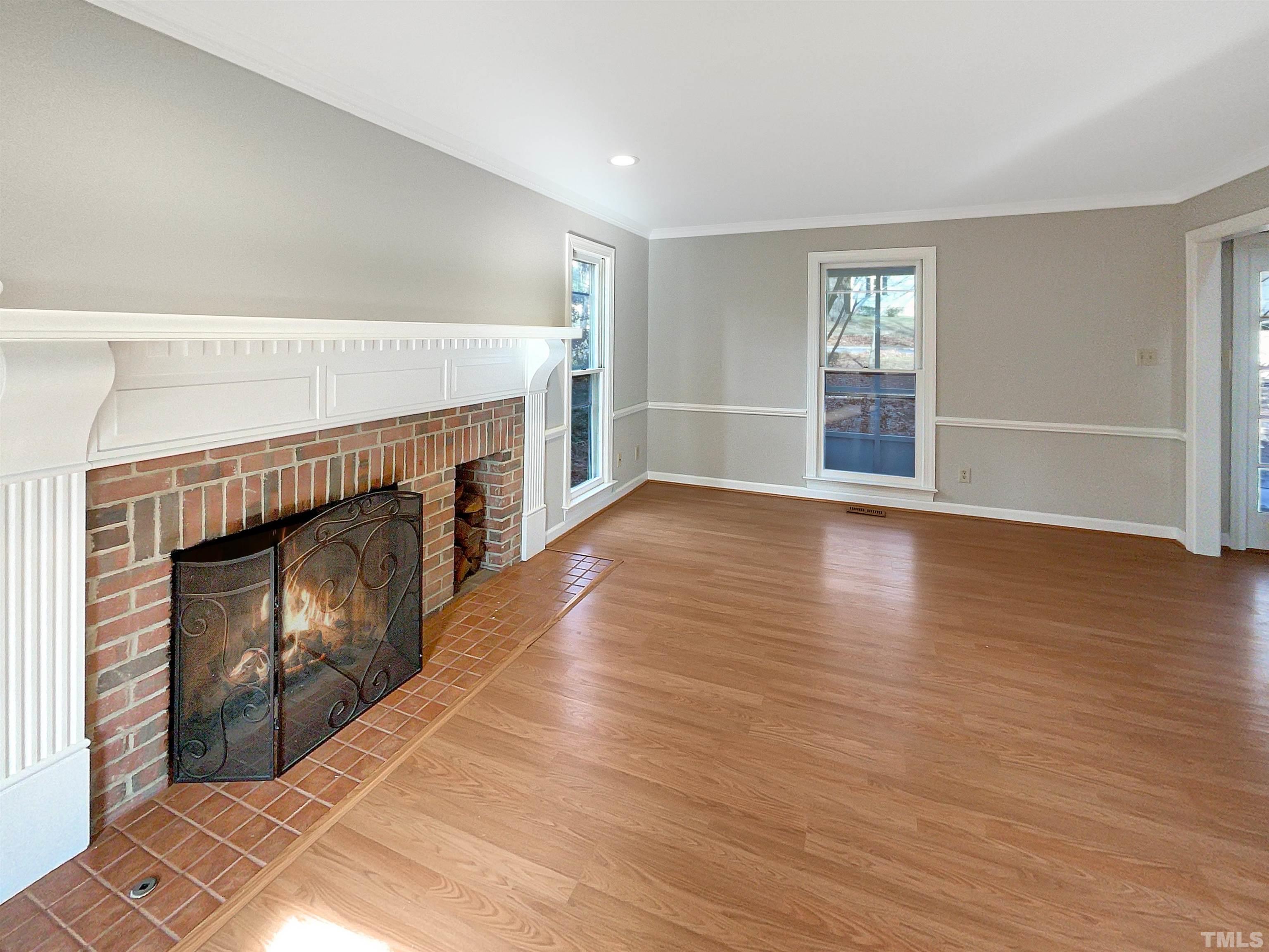 6900 Three Bridges Circle Raleigh, NC 27613 - Photo 8 of 20 an empty room with wooden floor fireplace and windows