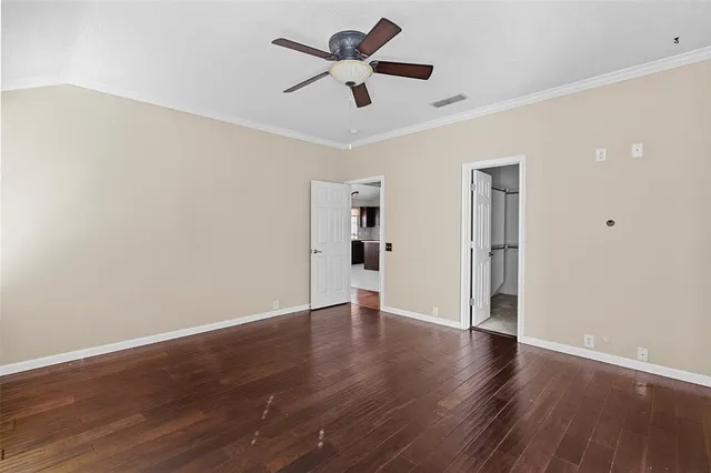 a view of an empty room with window a ceiling fan and wooden floor