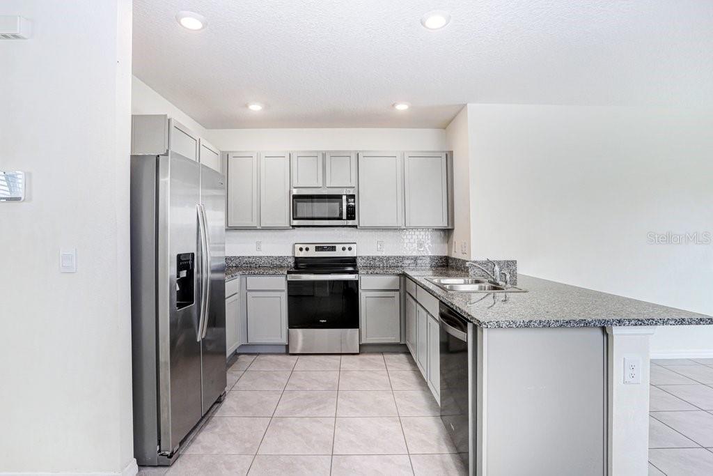 31210 Penny Surf Loop Wesley Chapel, FL 33545 - Photo 3 of 39 a kitchen with stainless steel appliances granite countertop a refrigerator sink and stove