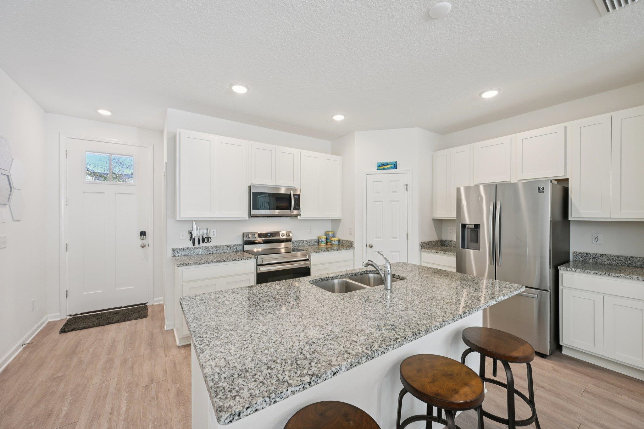 22 Ridge Lake Road St. Augustine, FL 32086 - Photo 4 of 31 Kitchen with stainless steel appliances, white cabinetry, light stone counters, light wood-type flooring, and recessed lighting