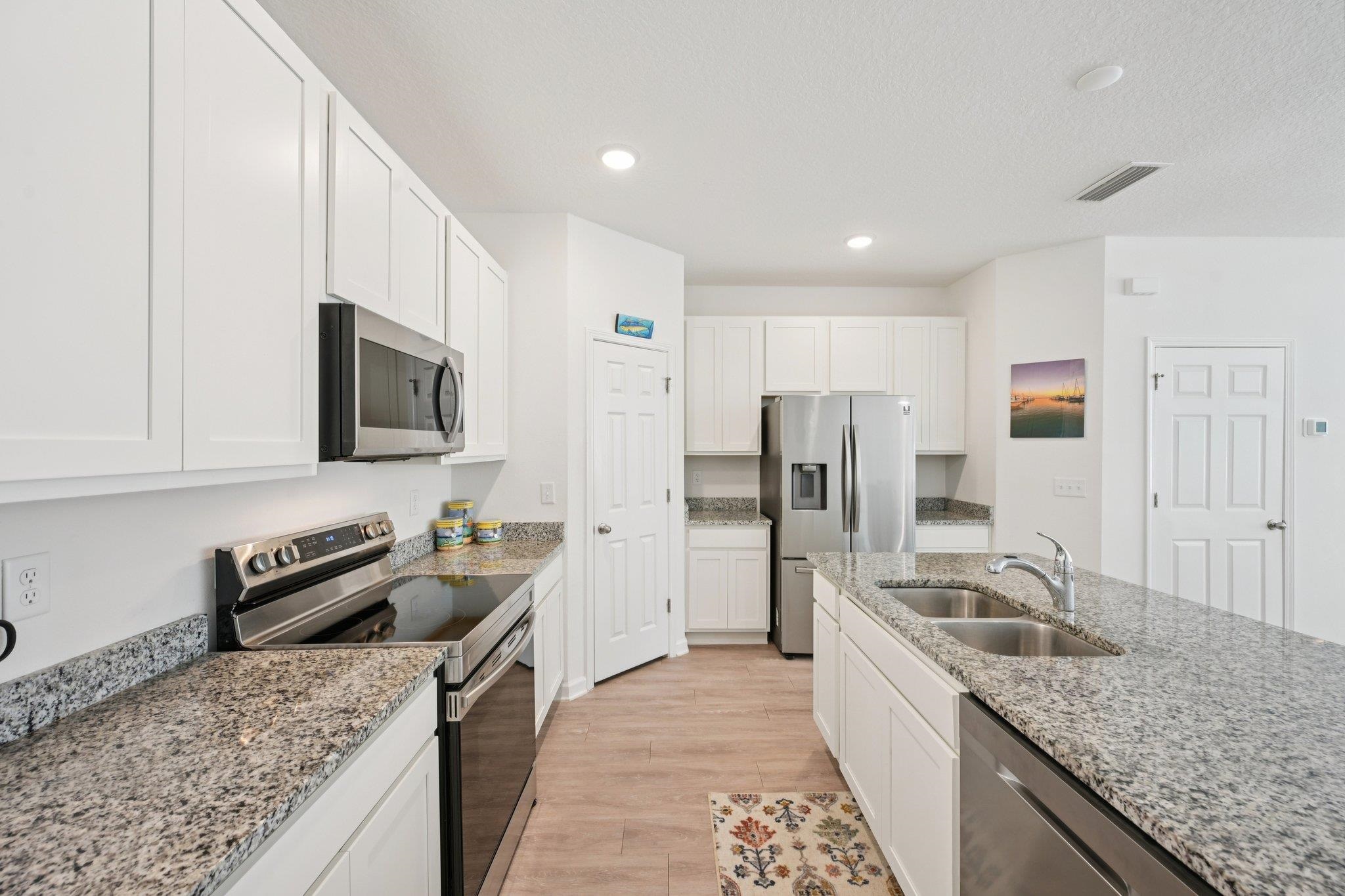 22 Ridge Lake Road St. Augustine, FL 32086 - Photo 5 of 31 Kitchen with stainless steel appliances, white cabinetry, light wood finished floors, light stone countertops, and recessed lighting